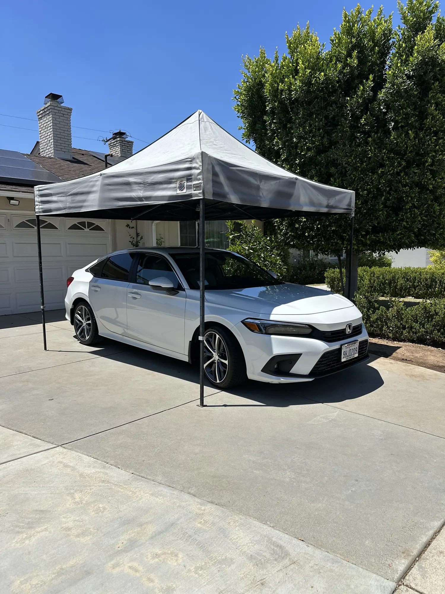 White Honda Civic detailed under a pop-up canopy